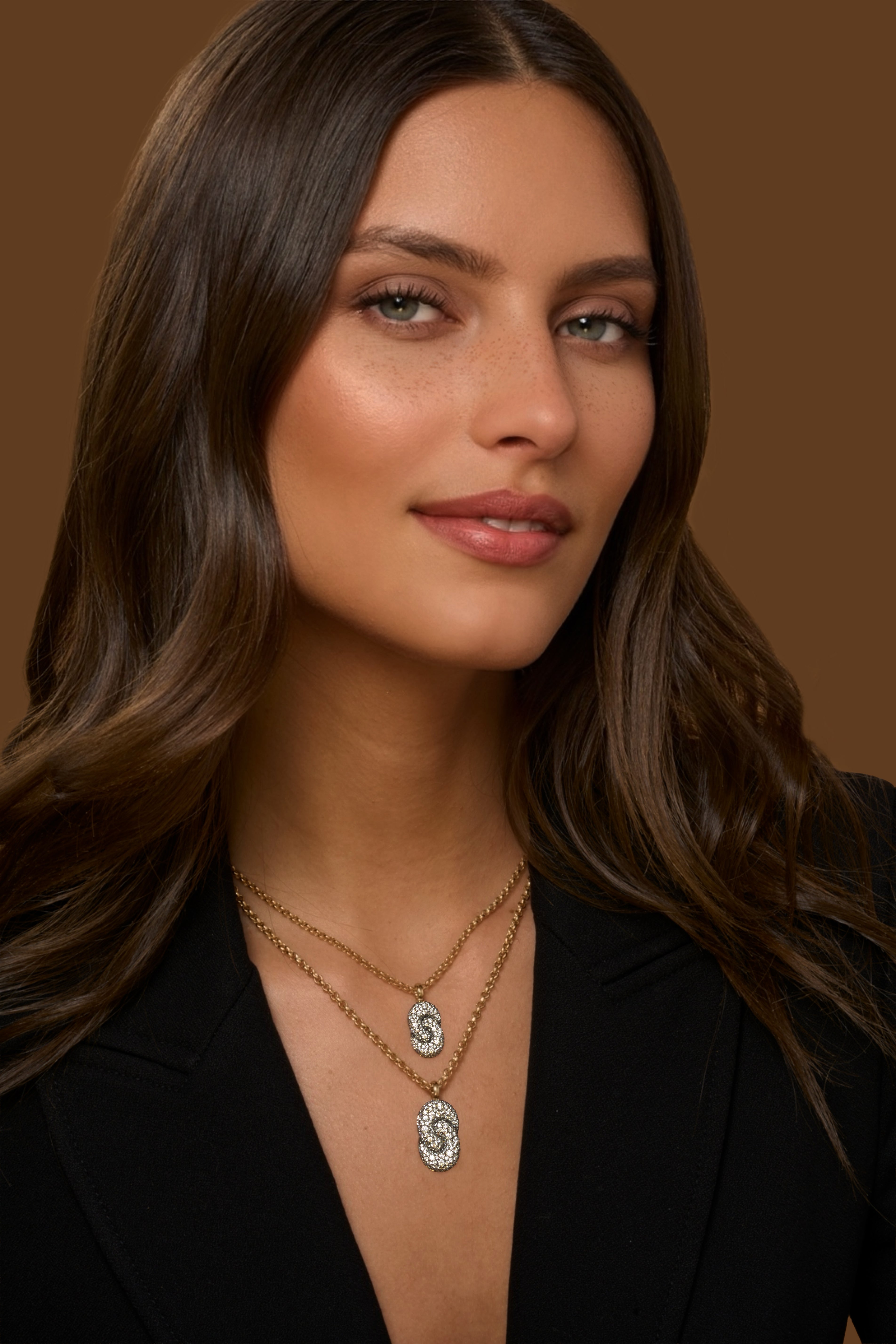 A close-up of a woman wearing the All Diamond Elongated Duet Necklace in 18k yellow gold with an elongated interlocking diamond pave pendant.