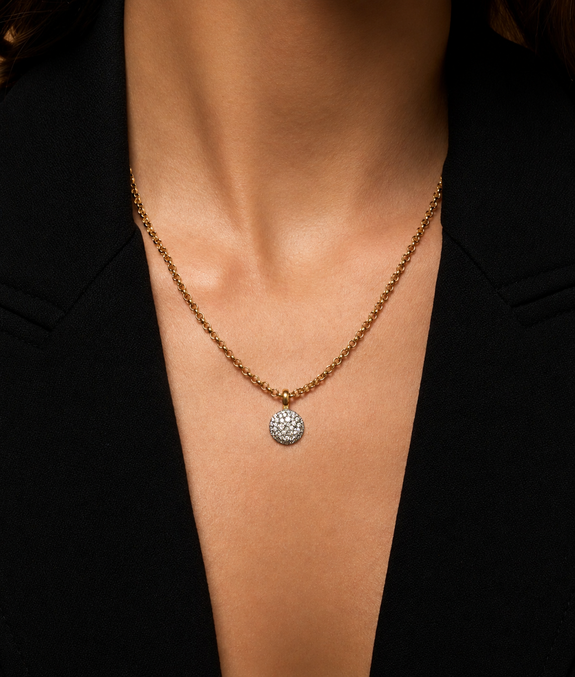 Close up of a model's chest wearing the Diamond Prima Necklace in 18k yellow gold with a round diamond pave pendant