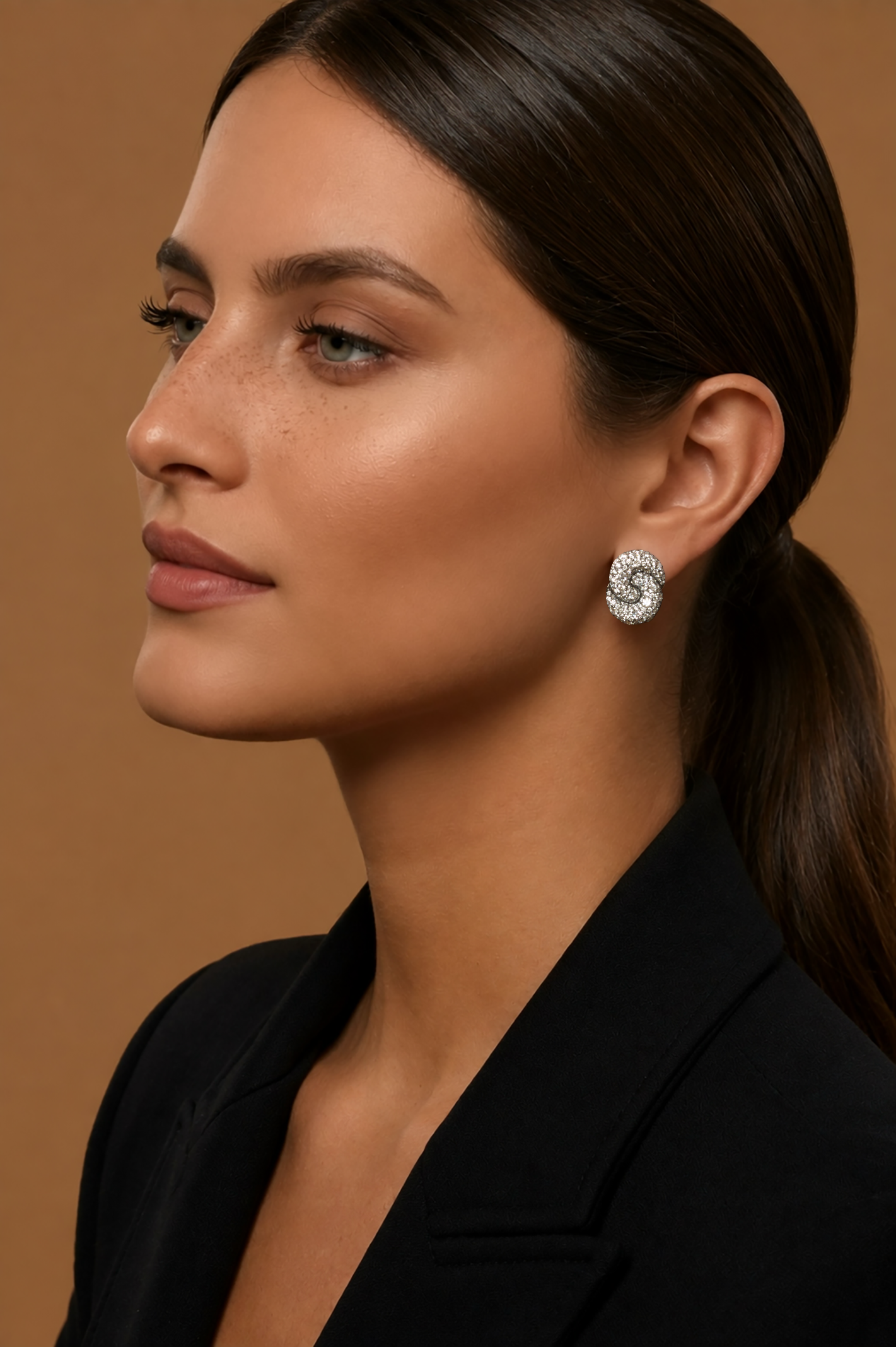 A close-up portrait of a woman wearing the Duet Diamond Stud Earrings with all-over colorless pave diamonds in the signature Duet silhouette.