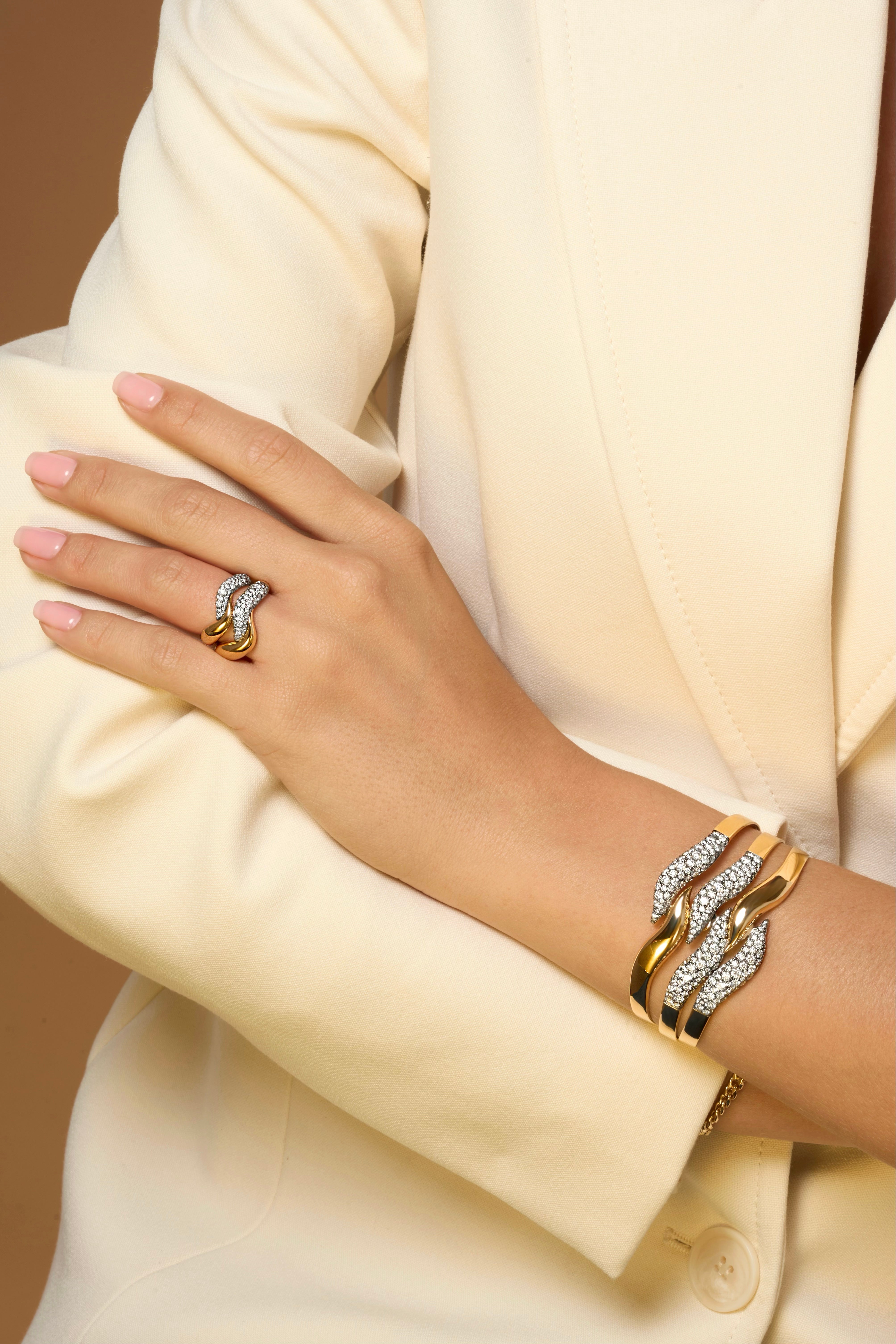 Hand wearing Dancer pieces in yellow gold with two curved pave diamond sections set in black rhodium.
